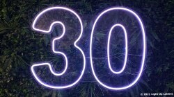 Neon number "30" displayed on a green leafy background.