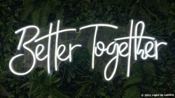 Neon sign reading "Better Together" against a background of green leaves.