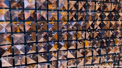 A wall display of multiple triangular medals, each with small tags attached, arranged in a grid pattern.