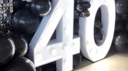 Large white marquee numbers "40" surrounded by black balloons.