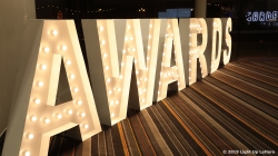 Illuminated letters spell out "AWARDS" on a striped floor.