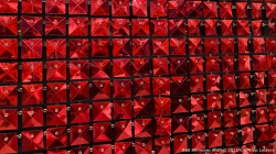 Close-up of red, square, reflective tiles arranged in a grid pattern, each with a small metal attachment at the top.