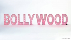 The word "Bollywood" is displayed in large, pink marquee letters with lights on a white background.