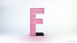 A pink, illuminated letter "F" with bulbs, standing upright on a black base.