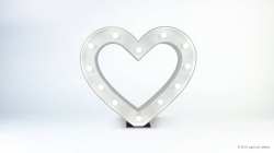 A white heart-shaped marquee light with small bulbs is centered against a plain white background.