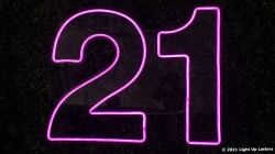 Neon pink number "21" sign illuminated against a dark background.
