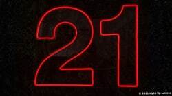 Red neon number "21" on a dark background.