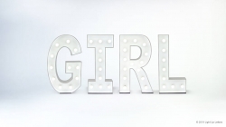 White marquee letters spelling "GIRL" with lit bulbs against a light gray background.